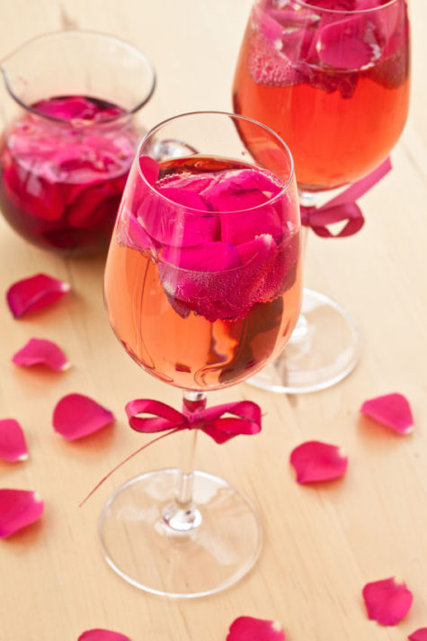 Pink Cocktail with fresh rose petals on wooden table