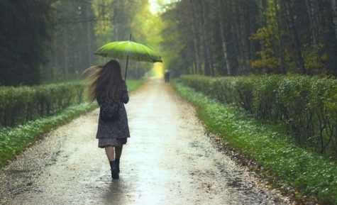 beautiful girl walking under rainfall in autumn park