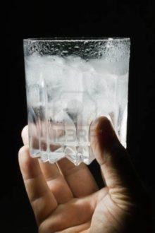 8810439-glass-of-vodka-with-ice-in-his-hand-on-a-black-background